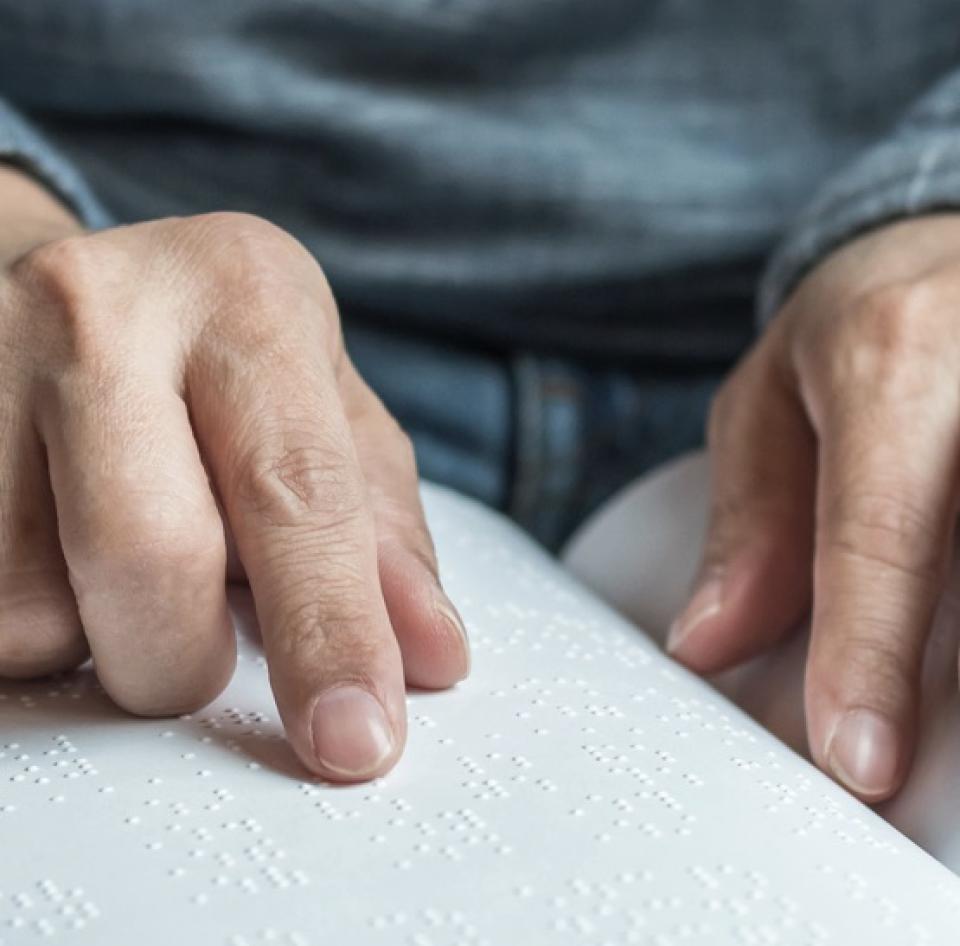 Manos de hombre leyendo braile